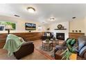 Cozy living room with a fireplace, wood paneling, and comfortable leather furniture at 8475 W 74Th Dr, Arvada, CO 80005