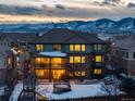 Home's rear view, showcasing a deck, yard, and mountain views at dusk at 11877 W Yale Pl, Lakewood, CO 80228