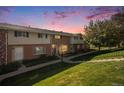 Brick townhome with green lawn, illuminated by a vibrant sunset at 9272 E Mansfield Ave, Denver, CO 80237