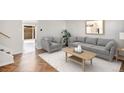 Bright living room with wood floors, gray sofa and chair, art, and a decorative coffee table at 9272 E Mansfield Ave, Denver, CO 80237