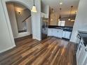 Open-concept kitchen with stainless steel appliances, wood floors, and staircase view at 12753 Ivanhoe St, Thornton, CO 80602