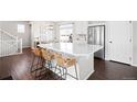 Bright kitchen features an island with barstool seating, white cabinetry, stainless steel appliances, and hardwood floors at 21925 E 44Th Pl, Aurora, CO 80019
