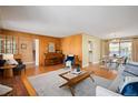 Open living room with hardwood floors connecting the dining area and featuring a brick fireplace at 588 Newark St, Aurora, CO 80010