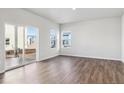 Bright living room with wood floors, large windows, and sliding glass door to backyard at 2161 Flower Blossom Ave, Brighton, CO 80601