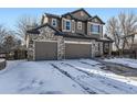 Two-story home with a brick and siding exterior, two car garage, and a snow covered front yard at 11701 Bent Oaks St, Parker, CO 80138