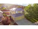 Aerial view of home, showcasing three-car garage, backyard, mature trees, and solar panels on the roof at 7627 Halleys Dr, Littleton, CO 80125