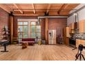 Open living room with exposed wood beams, brick walls, and stainless steel kitchen appliances at 2955 Inca St # 2Q, Denver, CO 80202