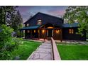 Charming home featuring a covered front porch, stone pathway, and lush landscaping with blooming purple flowers at 13416 Kuehster Rd, Littleton, CO 80127
