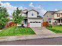 Charming gray two-story home with a manicured lawn and a two-car garage at 16048 Elizabeth St, Thornton, CO 80602