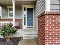 Inviting front porch featuring brick accents and a stylish gray front door at 16048 Elizabeth St, Thornton, CO 80602