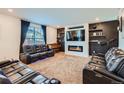 Modern living room with comfortable leather seating, entertainment center and cozy fireplace at 16048 Elizabeth St, Thornton, CO 80602
