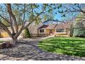 Lovely home features a lush green lawn, mature trees, and a welcoming facade with a vibrant red front door at 14072 W Alaska Dr, Lakewood, CO 80228