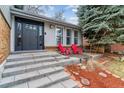 Close-up of a home's front entrance featuring gray steps and a door, and bright red chairs on the front porch at 7484 E Mercer Pl, Denver, CO 80237