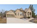 Stucco exterior featuring a tile roof, three car garage, and manicured landscaping around the home at 5035 Vermillion Dr, Castle Rock, CO 80108