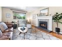 Cozy living room with hardwood floors, a decorative fireplace, and a large window offering natural light at 11224 W 28Th Pl, Lakewood, CO 80215