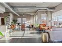 Open-concept living room with concrete ceilings, hardwood floors, and industrial-style ductwork and light fixtures at 1499 Blake St # 6K, Denver, CO 80202