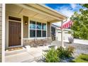 Inviting front porch showcases stone accents, outdoor seating, and a welcoming entrance to the home at 56459 E 23Rd Pl, Strasburg, CO 80136