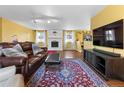 Spacious living room with a painted brick fireplace, modern lighting, and hardwood floors at 3280 S Ouray Way, Aurora, CO 80013