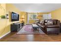 Cozy living room featuring a large brown leather sofa, area rug, and a bright window at 3280 S Ouray Way, Aurora, CO 80013