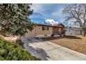 Tan brick home with an inviting driveway, complemented by mature trees for added charm at 2700 W 91St Ave, Denver, CO 80260