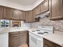 Efficient kitchen boasts abundant cabinet space, modern backsplash, and stainless vent hood at 2627 E Nichols Cir, Centennial, CO 80122