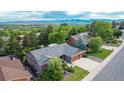 An aerial view of a single Gathering home surrounded by mature trees with mountain views in the distance at 8696 W Iliff Ave, Lakewood, CO 80227