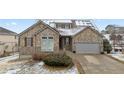 Charming home exterior boasting a stone facade, attached garage, and meticulously maintained landscaping in a winter scene at 1752 Peninsula Cir, Castle Rock, CO 80104