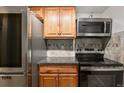 This kitchen features stainless steel appliances, wooden cabinets, and tiled backsplash at 14100 E Temple Dr # W04, Aurora, CO 80015