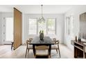 Dining room with a long black table, seating for six, a modern chandelier and three large windows at 4481 Raleigh St, Denver, CO 80211