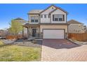 Charming two-story home with a well-manicured lawn and a brick driveway during daylight at 18366 E 102Nd Pl, Commerce City, CO 80022