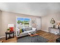 Bright living room featuring hardwood floors, a comfortable sofa, and a view of the neighborhood at 2465 W Mosier Pl, Denver, CO 80223