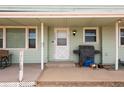 Close-up view of the front porch with a white door, dark grill, and miscellaneous items at 13654 County Road 13, Longmont, CO 80504