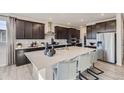 Stylish kitchen featuring dark cabinets, a large center island with seating, and stainless steel appliances at 14147 Bunny Hop Ln, Parker, CO 80134