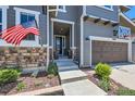 Inviting front entrance with American flag, well-kept landscaping and a dark wooden garage door at 10694 Cedarcrest Cir, Highlands Ranch, CO 80130