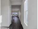 Bright hallway with dark wood floors and white walls leading to an open-concept living and dining area at 3961 Happy Hollow Dr, Castle Rock, CO 80104