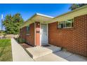 Exterior shot of a brick home's entrance with a concrete walkway, fresh landscaping, and an inviting front door at 2497 S Race St, Denver, CO 80210