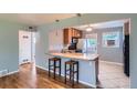 Bright kitchen with wooden cabinets, a breakfast bar with pendant lights, and an adjoining living area at 2497 S Race St, Denver, CO 80210