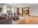 Bright living room with a large window, plush sofa, wood floors, and a doorway to a dining area at 25 High St, Palmer Lake, CO 80133