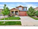 Inviting two-story home featuring a covered front porch and well-manicured lawn on a sunny day at 21502 E Idyllwilde Dr, Parker, CO 80138