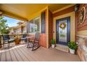 Cozy covered front porch with seating, plants, and a decorative wreath on the front door at 21502 E Idyllwilde Dr, Parker, CO 80138