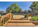 Wooden back deck overlooking a lush, well-maintained yard with mature trees, green grass, and a playhouse at 6708 W Portland Ave, Littleton, CO 80128