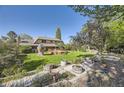 Large backyard featuring a wooden deck, mature trees, lush greenery, and a charming whimsical playhouse at 6708 W Portland Ave, Littleton, CO 80128