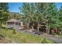 Beautiful home exterior showcasing a three-car garage, lush landscaping, and a welcoming covered porch at 3064 Elk View Dr, Evergreen, CO 80439