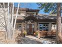 Charming home entrance with stone pillars, covered porch, and elegant wooden door at 3064 Elk View Dr, Evergreen, CO 80439