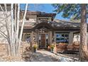 Inviting front entry featuring a covered porch, stone accents, and a beautifully crafted wooden front door at 3064 Elk View Dr, Evergreen, CO 80439