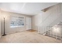 Bright living room features neutral carpet, a large window, staircase, and front door at 8915 Field St # 113, Westminster, CO 80021