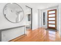 Bright foyer with hardwood floors, white walls, a round mirror and a modern wood door at 5086 N Raleigh St, Denver, CO 80212