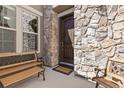 Inviting stone porch with seating and a decorative front door at 2363 S Lupine Way, Denver, CO 80228
