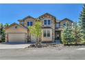Inviting two-story home boasts a stone and stucco facade, well-manicured landscaping, and a two-car garage at 791 Elk Rest Rd, Evergreen, CO 80439