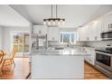 Bright kitchen with white cabinets, stainless appliances, island with granite countertops, and hardwood floors at 3999 W Chenango Ave, Littleton, CO 80123
